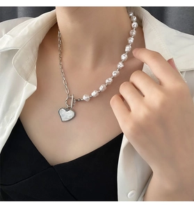 Detailed close-up of a heart-shaped pearl pendant necklace worn on a fashion model