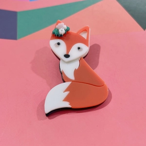 Cute orange acrylic fox brooch with flower details on a colorful geometric background