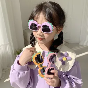 Detail view of cute dinosaur shaped children's sunglasses in purple, orange, and pink