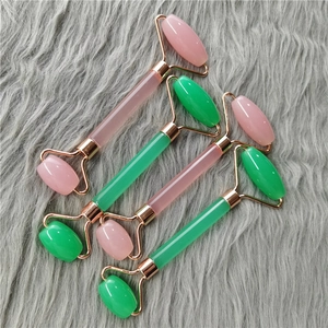 Close-up of pink and green quartz face rollers with rose gold metal frames on plush fabric