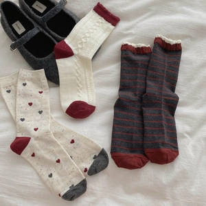 Close-up of heart patterns and cable knit textures on three pairs of red cotton socks