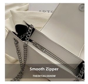 Detail view of the silver smooth zipper and stitching on the white leather shoulder bag