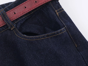 Détail d'un jean bleu foncé avec coutures contrastées et ceinture en cuir rouge