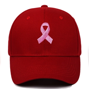 Detail showing high-quality red baseball cap with pink ribbon embroidery on front