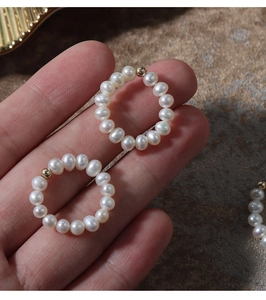 Detail of natural freshwater pearl ring with 14K gold-filled bead on stone background