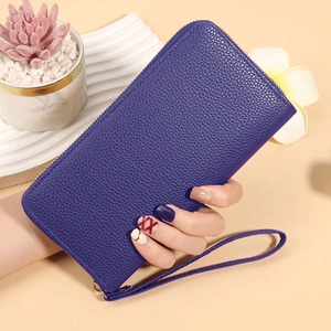 Detail of deep purple lychee pattern leather wallet with wristlet held by a person