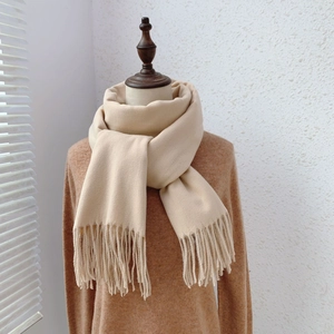 Detailed close-up of beige pashmina scarf with elegant tassels on a sweater mannequin