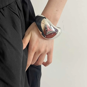 Moderner minimalistischer silberner Oversize-Manschettenarmreif am Handgelenk einer Frau