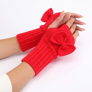 Close-up of red knitted fingerless gloves with bow detail and soft wool texture