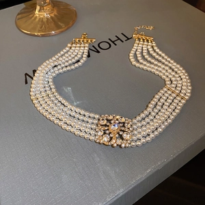 Detail of multi-layer pearl necklace with a rhinestone-encrusted gold square centerpiece