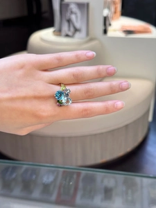 Detail of gold ring with vibrant blue and pink zircon clusters on hand