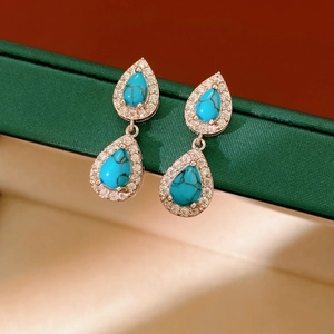 Macro detail of turquoise teardrop earrings with halo zircon settings in silver