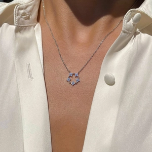 Détail d'un collier floral argenté avec une pierre opale ovale bleu clair sur modèle