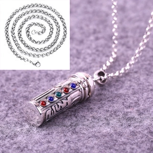 Detailed close-up of a silver cylinder pendant with colorful gems and embossed patterns