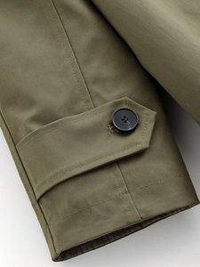 Detailed close-up of army green trench coat cuff with resin button and twill texture