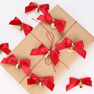 Macro view of decorative red satin ribbon bows with golden bells on a gift box