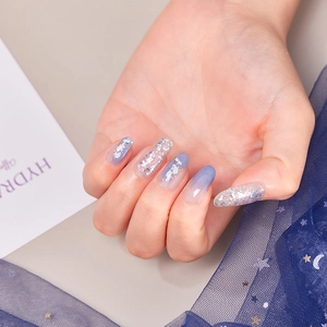 Detailed close-up of blue gradient long oval nails with silver glitter and sequins