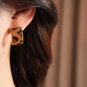 Gros plan de boucles d'oreilles léopard rectangulaires avec bordure dorée sur modèle