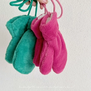 Detail of plush hanging mittens in vibrant colors with thick faux fur lining and cord