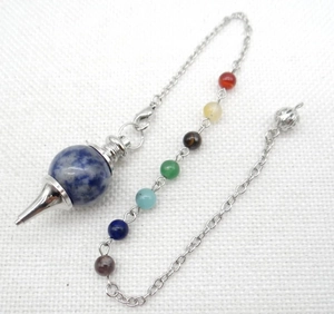 Macro detail of natural stone chakra pendulum with silver chain and seven energy beads