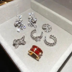 Elegant zircon bow ear cuffs and pearl drop earrings displayed on a velvet jewelry tray