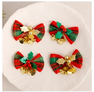 Set of four red and green plaid Christmas bow ornaments with golden bells on white tray