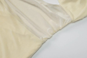 Detailed close-up of beige dress side cut-out featuring soft mesh lining and ruched fabric