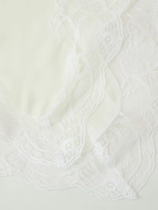 Close-up of the delicate white lace stitching and textured fabric on the camisole top