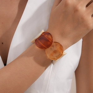 Detail of amber acrylic geometric bracelet on model's wrist with vintage resin charms