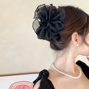 Détail d'une pince à cheveux en tulle noir multicouche portée par un mannequin de profil