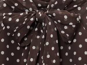 Detail of sheer dark brown chiffon fabric with white polka dots and a bow tie knot