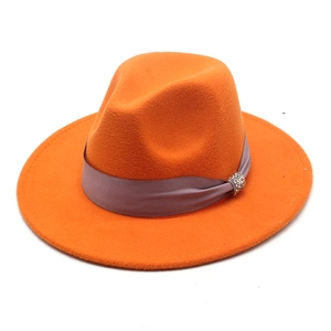 Detail of orange wool fedora hat with silk ribbon and crystal rhinestone ornament