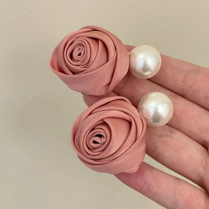 Détail de boucles d'oreilles élégantes en satin rose et grandes perles blanches