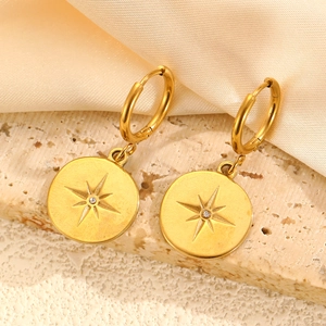Gros plan de boucles d'oreilles créoles dorées avec pendentifs étoile sur soie