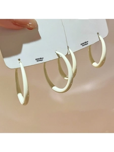 Detail of cream white C-shaped hoop earrings with S925 silver needles on a display card