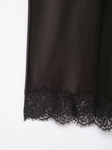 Gros plan d'un ourlet en satin noir avec bordure en dentelle de cils délicate