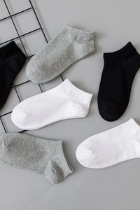 Flat lay of black white and grey cotton low cut ankle socks on a minimalist background