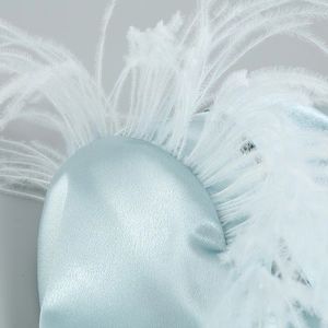 Gros plan détaillé du tissu en satin bleu clair et des plumes blanches délicates du haut
