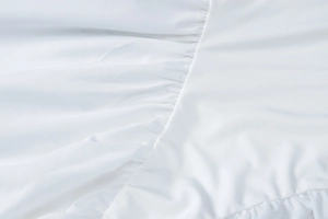 Detailaufnahme von weißem Stoff mit Nähten und Falten-Design bei einem tiefen V-Ausschnitt Kleid