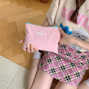 Detail of pink fabric makeup bag with Sozanna label and contrasting blue zipper accents