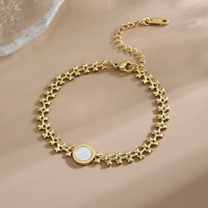 Detail of gold bracelet featuring X-links and white mother-of-pearl center with K18 tag