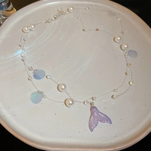 Macro detail of mermaid tail pendant with pearlescent beads and blue iridescent discs