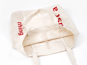 Detail view of canvas tote bag interior showing the open inner pocket and red text design
