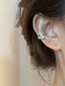 Detail of silver leaf ear cuff with cubic zirconia worn on the upper ear cartilage