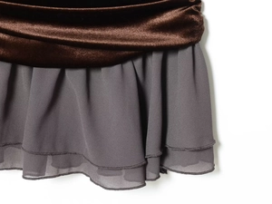 Detail van de bruine fluwelen taille en grijze gelaagde chiffonstof op een nauwsluitende jurk