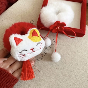 Detail of plush cat hair scrunchie set with red tassels and soft white pom poms
