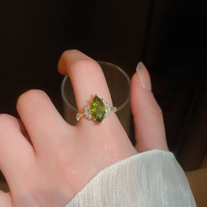 Detail of 14K gold-plated ring with olive green marquise gemstone and crystal accents