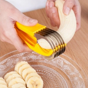 Manual stainless steel banana slicer with yellow handle cutting fruit over a glass bowl
