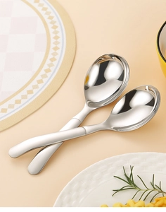 Macro shot of two polished stainless steel spoons crossed on a dining table setup