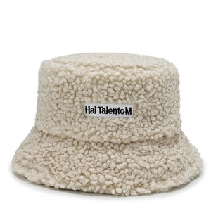 Detailed view of cream faux lamb wool bucket hat with black embroidered brand patch